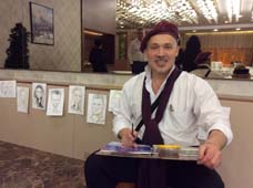 Художник сидит на фоне своих рисунков